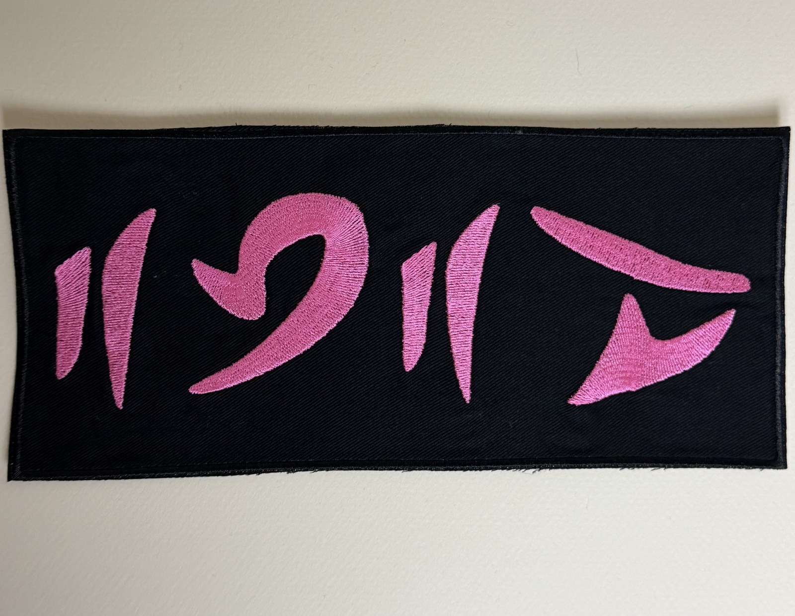 Large custom embroidered patch with pink alien-style lettering on black fabric, made for a Coldplay cover band in Europe
