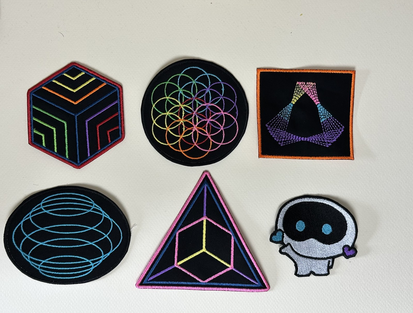 Six custom embroidered patches in bright thread on black backgrounds, designed for a Coldplay cover band in Canada